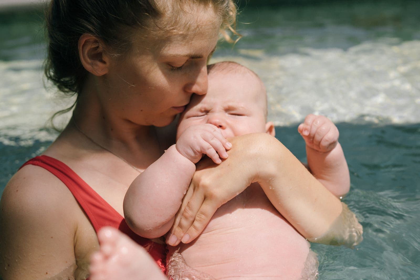 Parent holding their young child close in a swimming pool