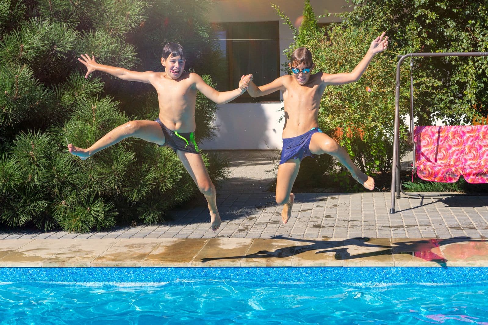 Two boys jumping hand-in-hand into a swimming pool